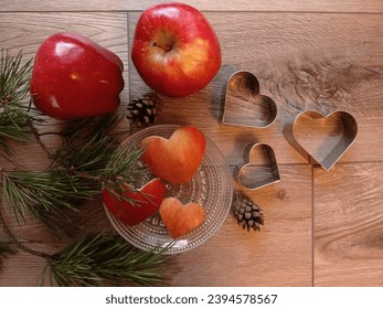 Top view of some christmas elements: apples, cookie cutters, pine branches, pine cones and heart shaped apple cutouts made with cookie cutters. - Powered by Shutterstock