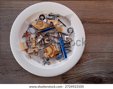 Top view of some miscellaneous items like screws and pins on a white plait.