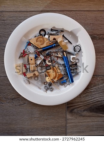 Top view of some miscellaneous items like screws and pins on a white plait.