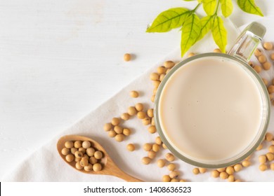 Top View Of Soy Or Soya Milk In A Glass With Soybeans In A Wooden Bowl Background