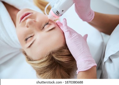 Top view of a spa client undergoing the cosmetic procedure performed by an experienced doctor