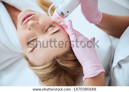 Top view of a spa client undergoing the cosmetic procedure performed by an experienced doctor