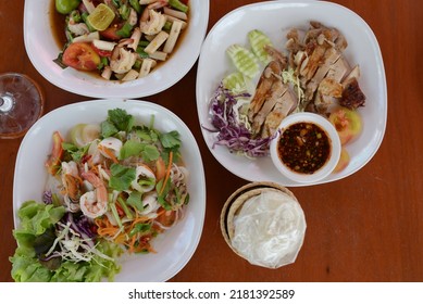 Top view of spicy food  lunch consists of salad flow lotus (root lotus) with boiled shrimp, grilled chicken with Thai spicy sauce in a cup, Seafood Glass Noodle Salad served with sticky rice in basket
