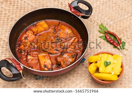 Top view of spicy and hot king fish curry and cooked tapioca or Cassava root, Mandioca, Aipim, green curry leaf Kerala India. Barracuda Fish curry, red chili powder, coconut milk Asian cuisine food.