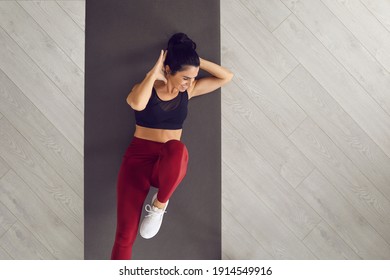 Top view of sporty active woman doing cross training bicycle crunches trains leg muscles and abs. Athlete conducts daily training on a mat in the room. Banner. Place for text. Article for website.