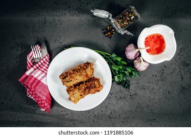 Top View Of Spring Rolls On A White Plate. Spring Rolls, Springroll Dressing And Food Ingredients On A Dark, Stone Counter Top. The Concept Of Serving Dishes, Eating Spring Rolls.