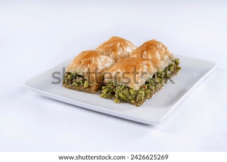 Top view of square baklava with pistachio on white plate isolated on white background.