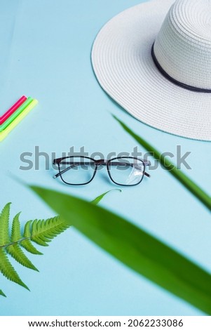 top view. square glasses, green leaves, dry leaves. hat , colored pencils on a pastel color background
yellow and pink.