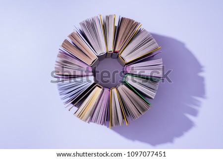 top view of stack of books in circle on violet tabletop