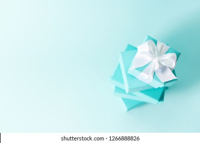 Top View Of Stack Of Boxes Tied With Silk Ribbon, Lying On Each Other On Tiffany Blue Color Pastel Background. Gift Festive Selection.