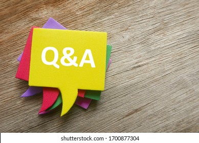 Top view stack of colorful speech bubbles with the top written with Q&A or questions and answers on wooden background.