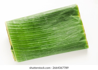 Top view stack of fresh, folded daun pisang (banana leaves) on a white background.