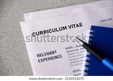 Top view of stack of office documents including resume and cv forms on the desk close to pen and notepad. Job seeking process. Hunting for workplace concept