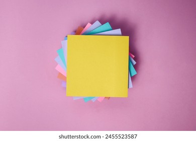 Top View of Stacks of Colorful Sticky Notes with Yellow Color Notes in Front Isolated on Pink Background. 