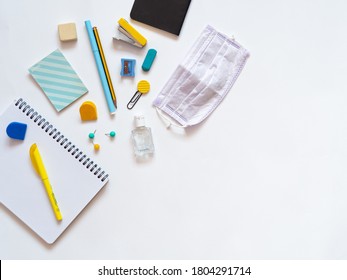 Top View Of Stationery Supplies During Covid Isolated On White Background. Student's Desk With School Supplies As Notebooks And Face Mask. Back To School Concept During Coronavirus. Copy Space.