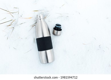 Top View Of Steel Reusable Thermos Near Bottle Cap On Snow.