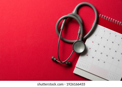 Top View Of Stethoscope And Calendar On The Red Background, Schedule To Check Up Healthy Concept