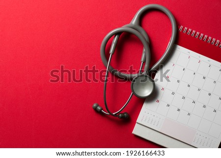 Top view of stethoscope and calendar on the red background, schedule to check up healthy concept Stock fotó © 