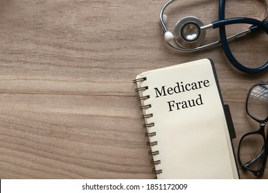 Top View Of Stethoscope, Glasses And Notebook Written With Medicare Fraud On Wooden Background With Copy Space.