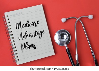 Top view of stethoscope and notebook written with text MEDICARE ADVANTAGE PLANS over red background. - Shutterstock ID 1906738255