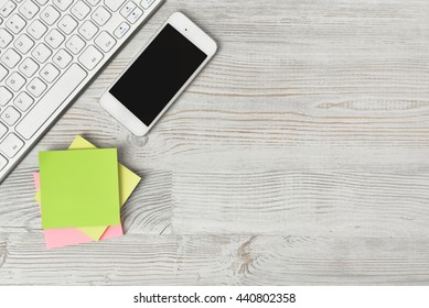 Top View Of Stickers, Keyboard And IPhone On Wooden Surface. Workplace Of Office Man. Office Stuff. Poor Memory Reminders. Organizer.