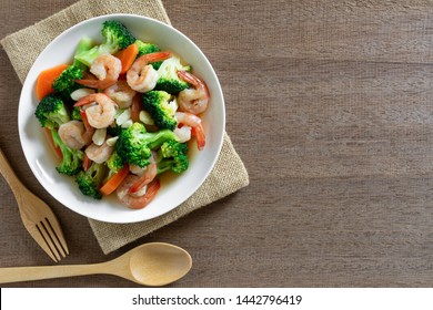 top view of stir fried broccoli with shrimps in a ceramic dish on wooden table. homemade style food concept.