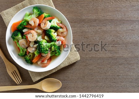 top view of stir fried broccoli with shrimps in a ceramic dish on wooden table. homemade style food concept.