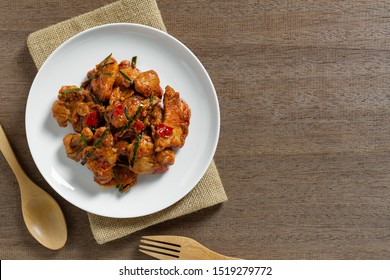 Top View Of Stir Fried Chicken With Red Curry Paste In A Ceramic Dish On Wooden Table. Hot And Spicy Thai Style Food Menu.