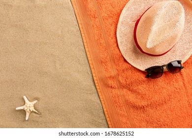 Top view straw hat and sunglasses with copy space. Traveler accessories on sand. Travel vacation concept. Summer background. Border composition made of towel