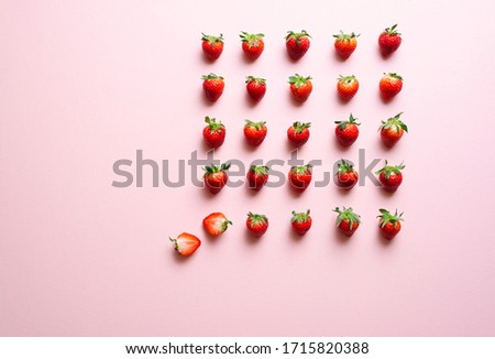 Top view with strawberries aligned symmetrically on a pink background. Fresh organic strawberries with green leaves.