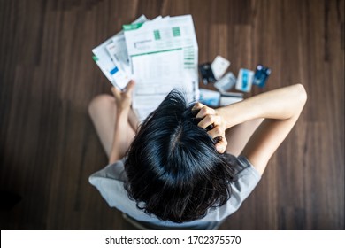 Top View Of Stressed Young Asian Woman Hands Holding The Head Trying To Find Money To Pay Credit Card Debt And All Loan Bills. Financial Problem From Coronavirus Or Covid19 Outbreak Crisis Concept.