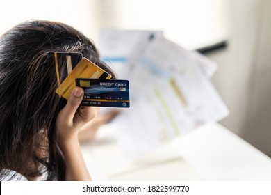 Top View Of Stressed Young Asian Woman Hands Holding The Head Trying To Find Money To Pay Credit Card Debt And All Loan Bills. Financial Problem From Coronavirus Or Covid19 Outbreak Crisis Concept.