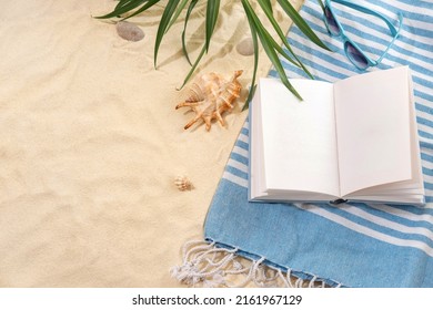 Top view of striped blue towel with book and sunglasses on sandy beach. Background with copy space and visible sand texture. - Powered by Shutterstock