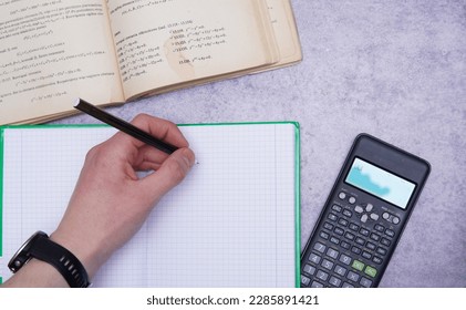 top view of a student solving a math problem. Close up of a book, pen and calculator. Advanced integral problems