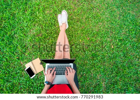 Top view of a studient woman sitting on the green grass in a par