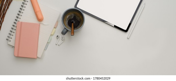 Top view of study table with mock up tablet, stationery, coffee cup and copy space on white desk 