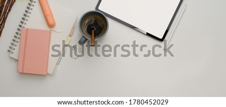 Top view of study table with mock up tablet, stationery, coffee cup and copy space on white desk 