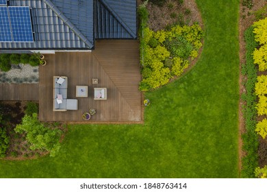 Top View Of Suburban House With Green Garden And Wooden Terrace