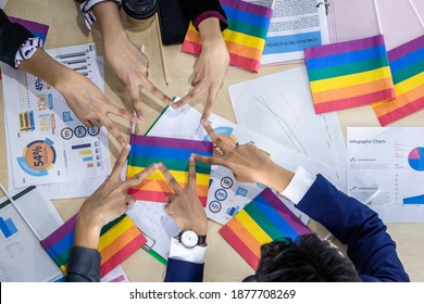 Top View Successful Workers Group Of Asian Business Partners With Diverse Genders (LGBT) Putting Their Hands Together With Paper LGBT Flag At It At Meeting In The Room At Office,