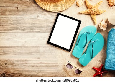 Top view of summer accessories and blank tablet on wooden planks - Powered by Shutterstock