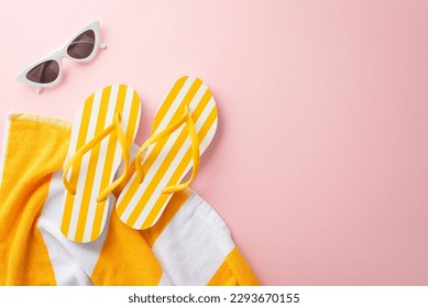 Top view of summer accessories concept. Flat lay of yellow striped flip-flops, towel, vintage sunglasses on pastel pink background with empty space for text or advert
