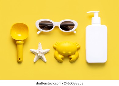 Top view of sunglasses,starfish,sunscreen and beach toys over yellow background. Summer holiday concept - Powered by Shutterstock