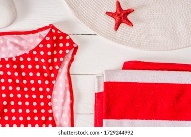 Top view of swimsuit near striped towel, sun hat and red starfish on white wooden surface - Powered by Shutterstock