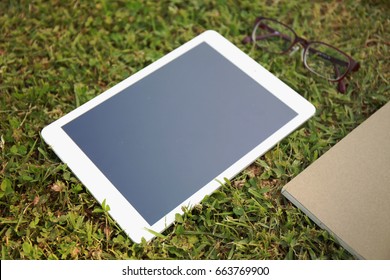 Top view table and book with a tablet of grass.