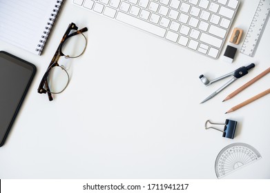 Top View Table Desk Of Office Architect Pencil, Compasses Tool, Ruler, Rubber, Protractor Grid, Sharpener, Glasses, Smartphone, Keyboard With Copy Space Background.