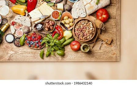 Top view table full of food. Italian antipasti wine snacks set. Cheese variety, nuts, Mediterranean olives, sauces, Prosciutto vegatables and berries and wine over wooden background