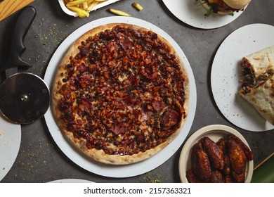 A Top View Of The Table With Pizza, Chicken Wings, And Burritos