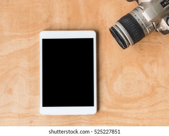 Top view of tablet with camera on wooden table.