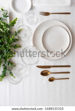 Top view of tableware with linen napkins, gold cutlery and white porcelain plates. Minimalist table settings background for dinner.