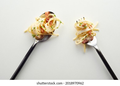 A top view of tasty pasta carbonara on a fork and spoon in the white background - Shutterstock ID 2018970962